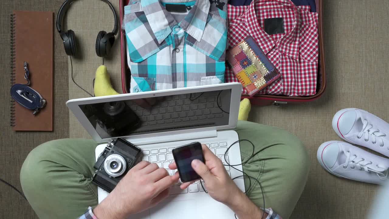 旅行家正在打包行李，用笔记本电脑工作视频下载