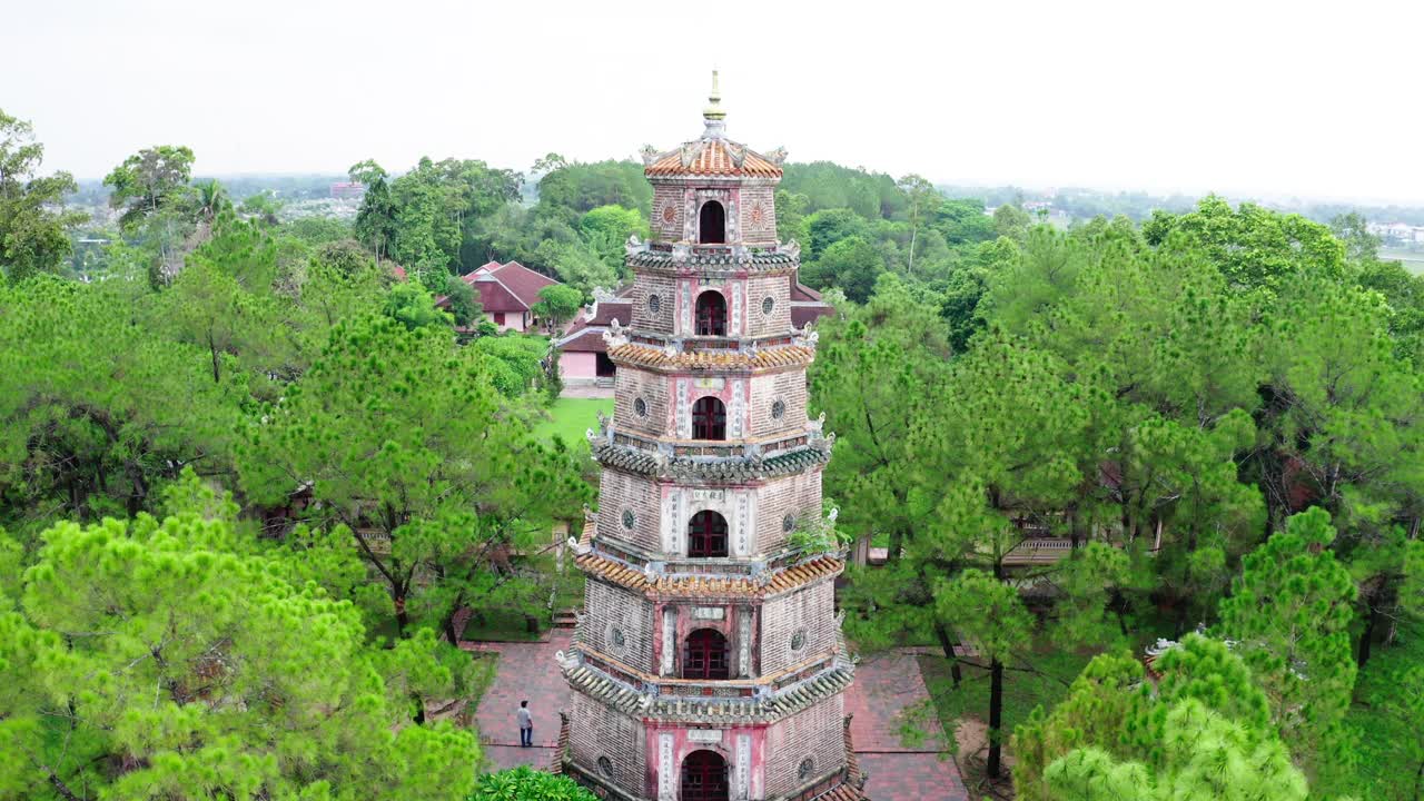 空中倾斜拍摄游客在著名的天目宝塔，无人机上升在绿树中流行的地标-顺化，越南视频下载
