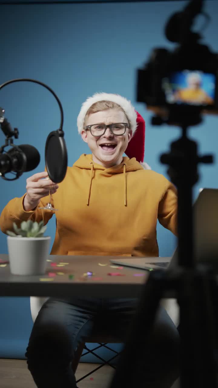 一个欢快的年轻博主在为他的频道拍摄圣诞场景时，在蓝色背景的演播室里引爆了一个圣诞爆竹视频下载