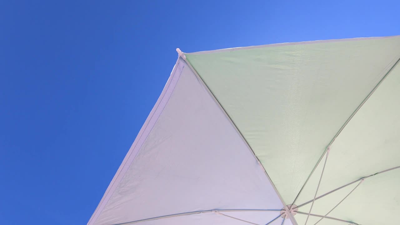 低角度的太阳伞遮阳伞在海滩与蓝色的天空在背景视频素材