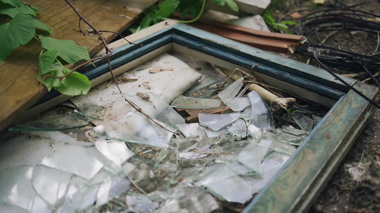 地上有碎玻璃的窗框。废弃的建筑物旁视频下载