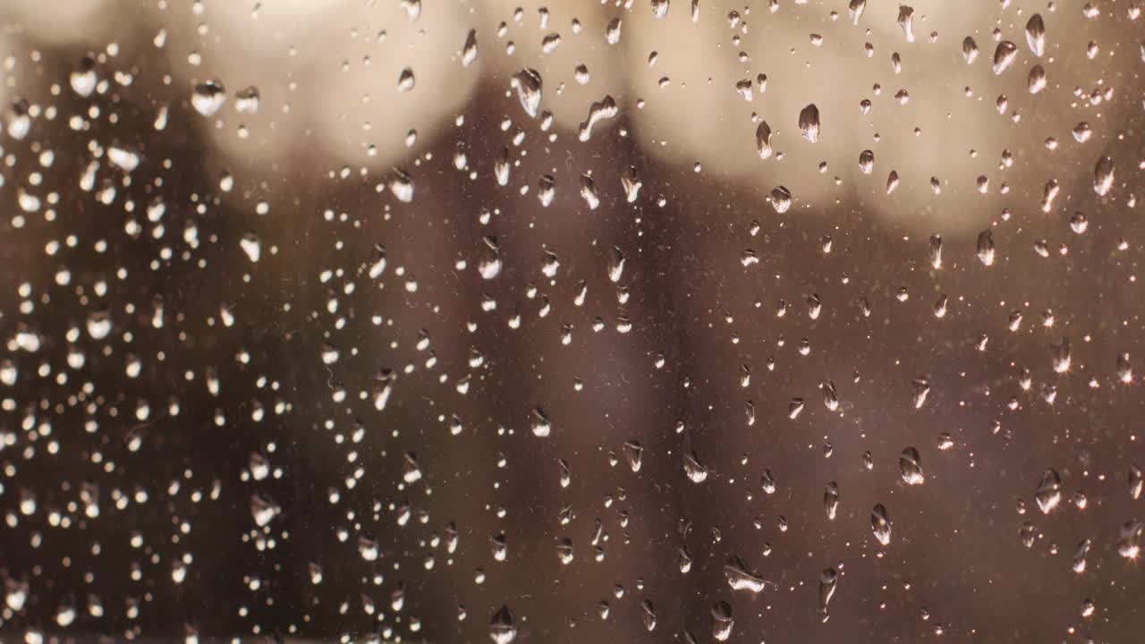 在一个晴朗的日子里，一扇被雨滴覆盖的窗户的特写，用4K拍摄视频下载