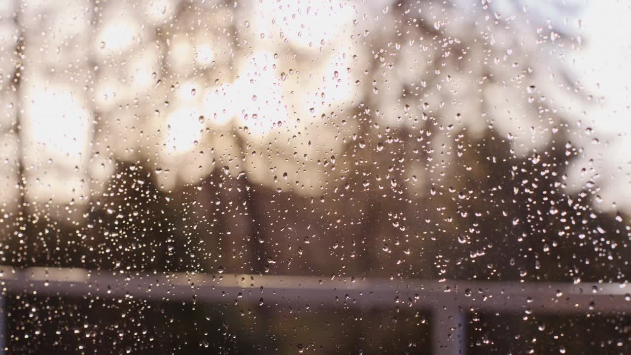 在一个晴朗的日子里，一个窗户被雨滴覆盖的特写镜头，用4K拍摄视频下载