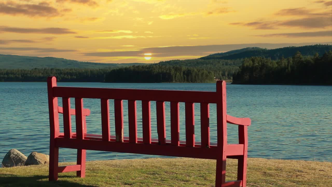 孤独的红色木凳在日落与绿色的山脉背景在高清视频下载