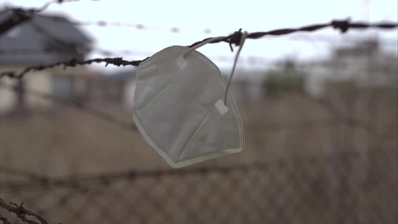 一个面具挂在铁丝网上，在风中摇摆的4K特写镜头视频下载