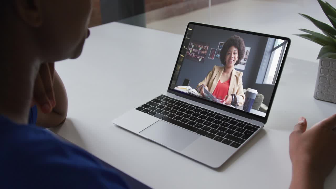 一名非洲裔美国女性正在办公室的笔记本电脑上与女同事进行视频通话视频下载