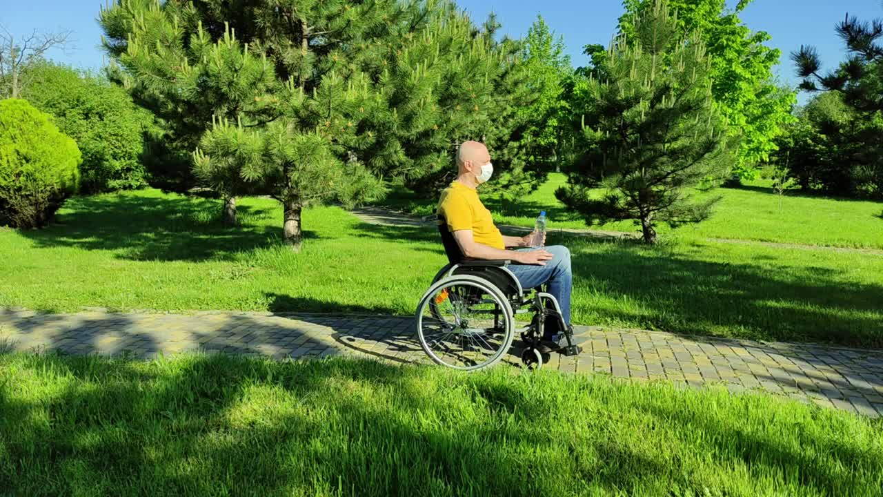 残疾人坐在轮椅上在公园里休息。视频下载
