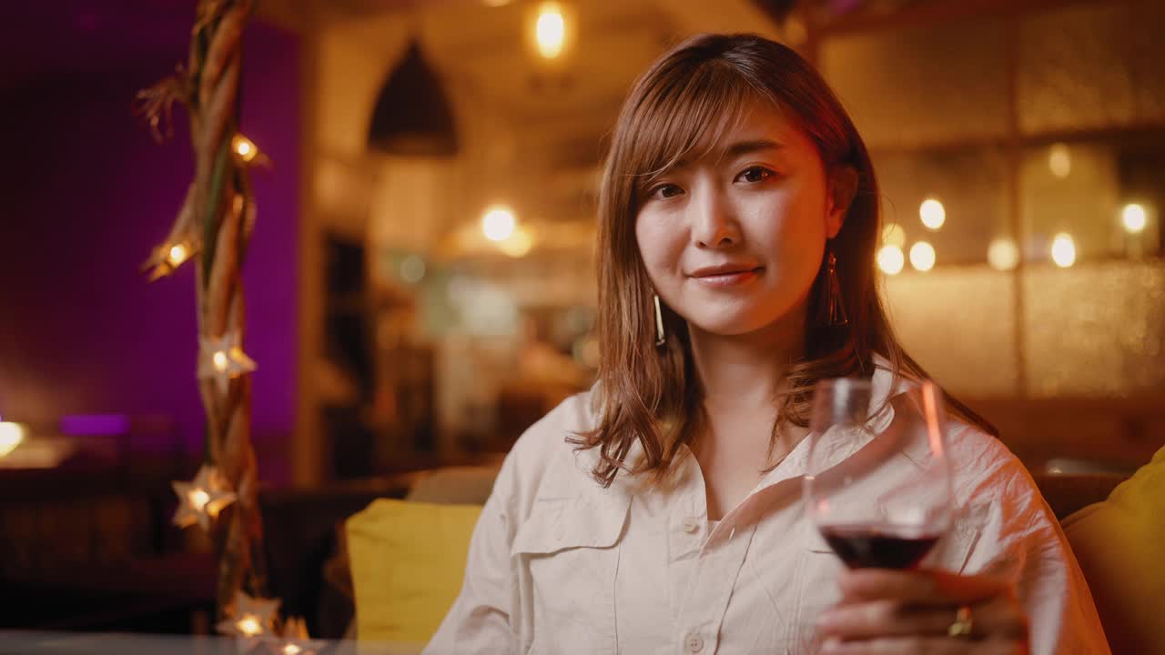 在咖啡厅和酒吧用笔记本电脑工作的女人拿着红酒的肖像视频下载