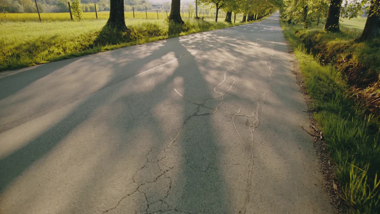 一个年轻人骑着滑板穿过乡间小路视频下载