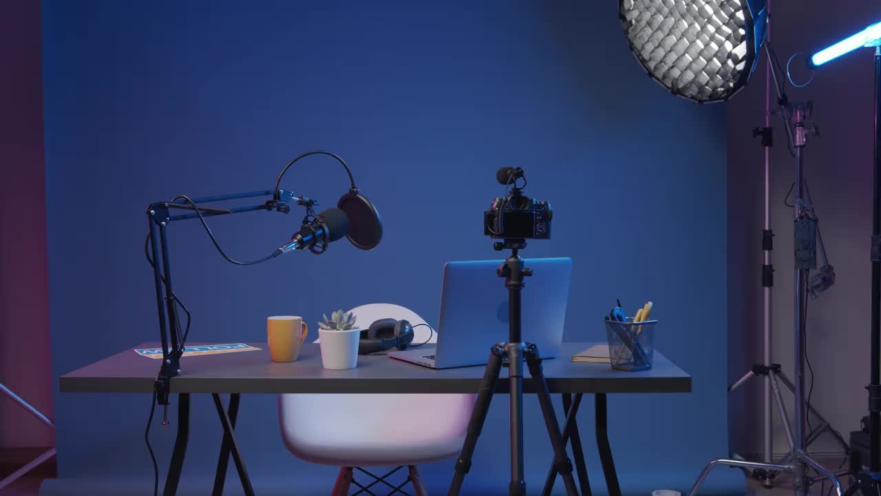 一个专业的录音棚，蓝色背景下的桌子上放着相机、笔记本电脑和麦克风视频下载