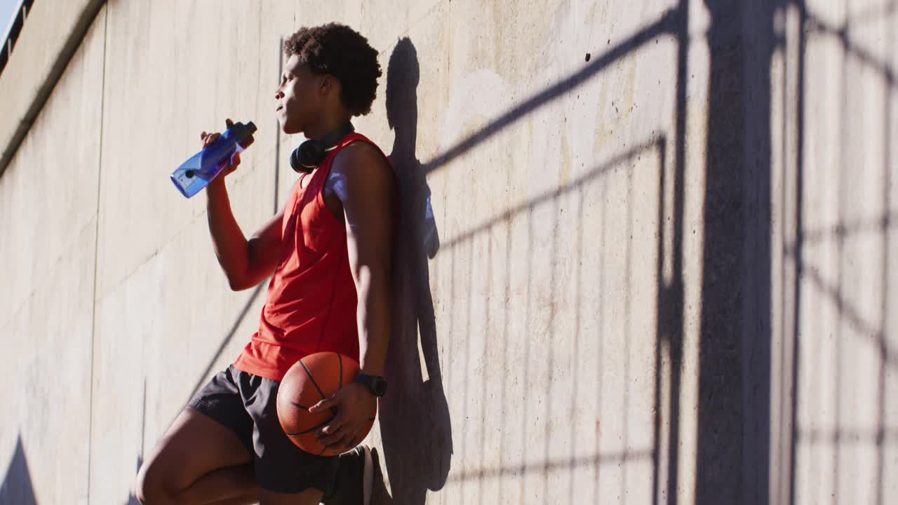 健康的非裔美国人在城市锻炼休息，喝水，拿篮球视频下载