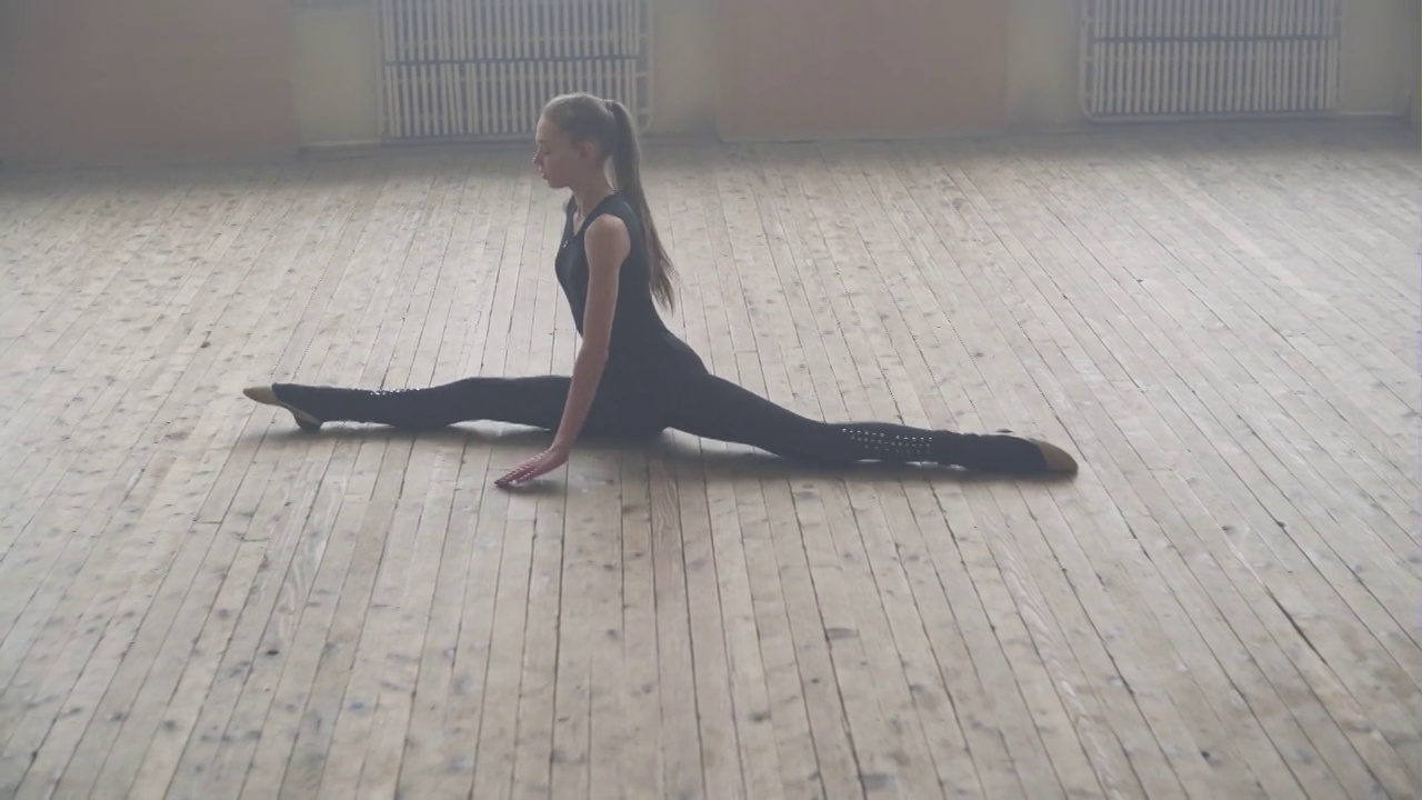 美丽的年轻女孩做伸展运动在芭蕾舞学校在一个复杂的杂技舞蹈视频下载