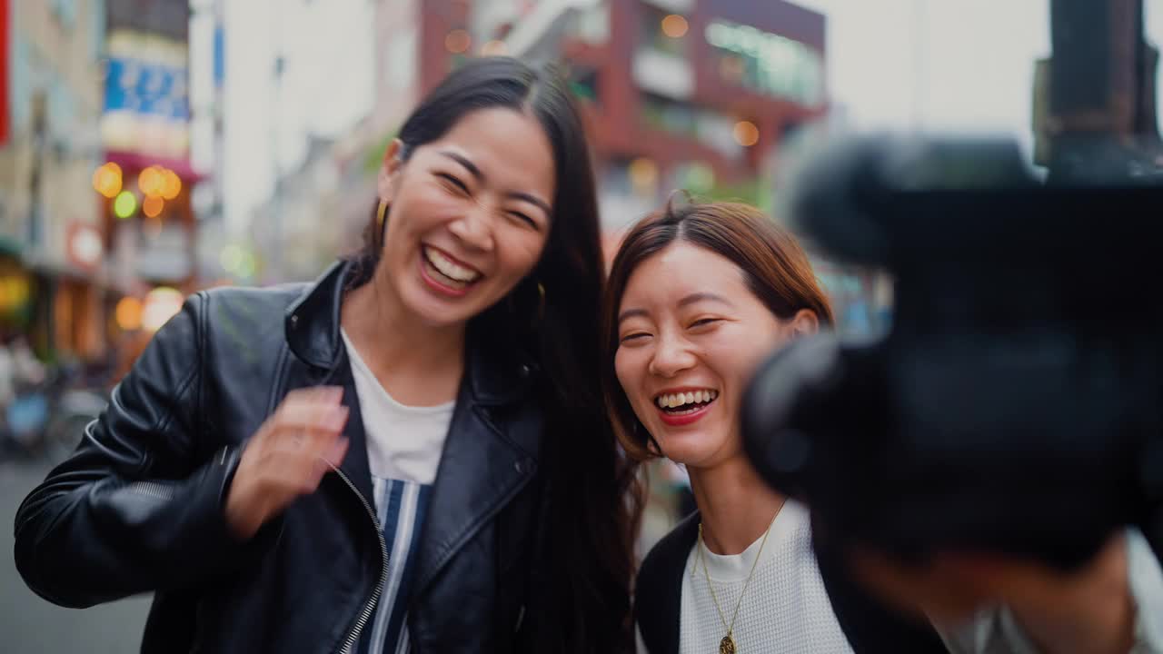 两个女性朋友带着数码相机在城市里拍视频视频素材