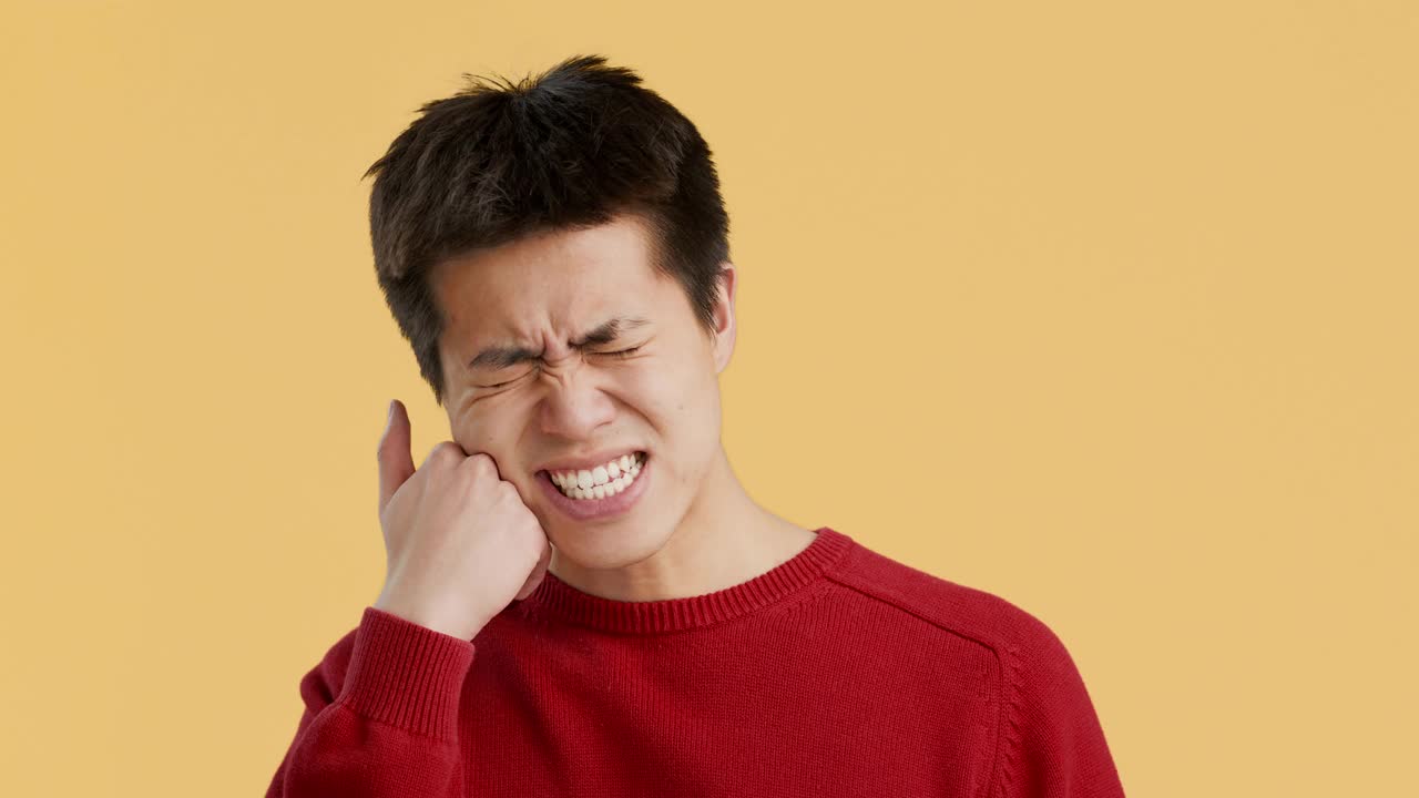 中国男子牙痛，橙色背景视频下载