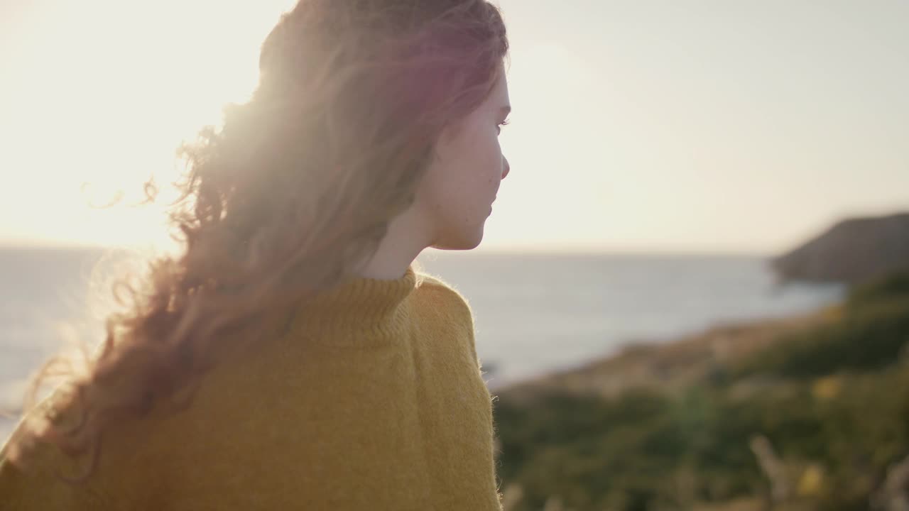 一个年轻的女人在海上看日落视频素材