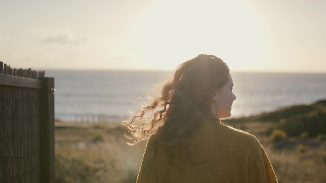 日落时分，一个女人在木板路上走向大海视频素材