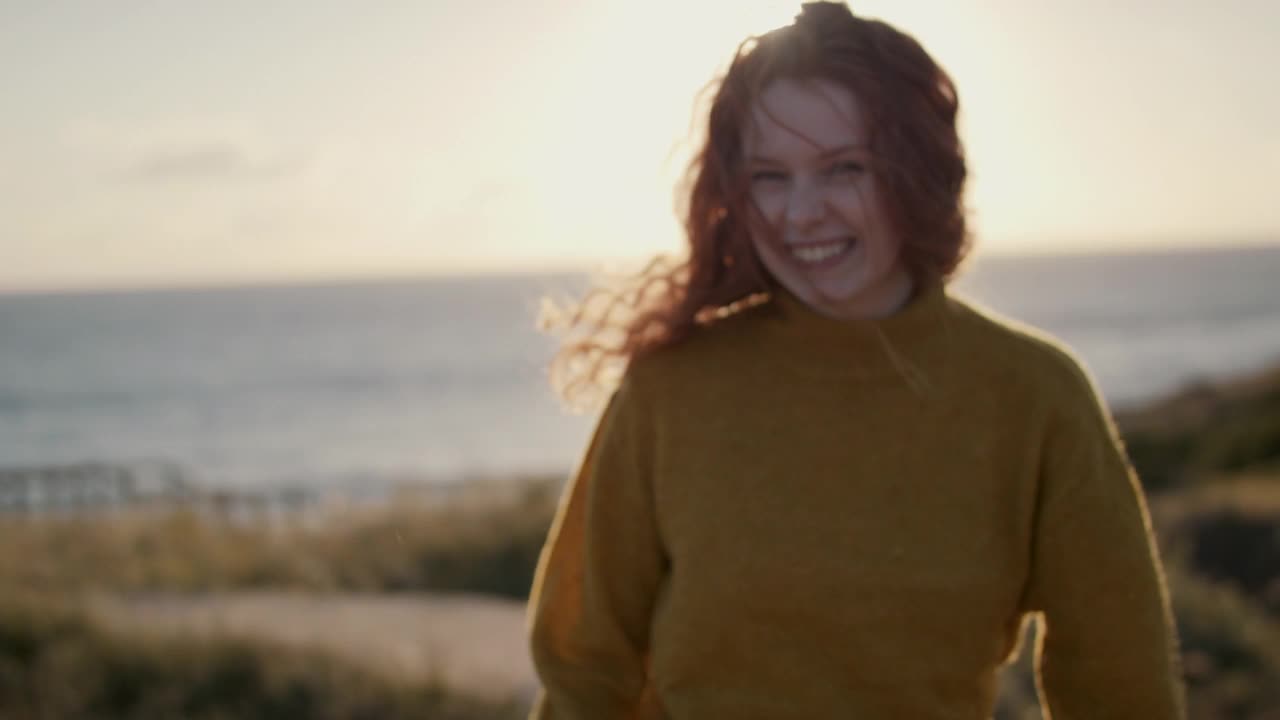 一个女人笑着走在木板路上去海滩视频素材