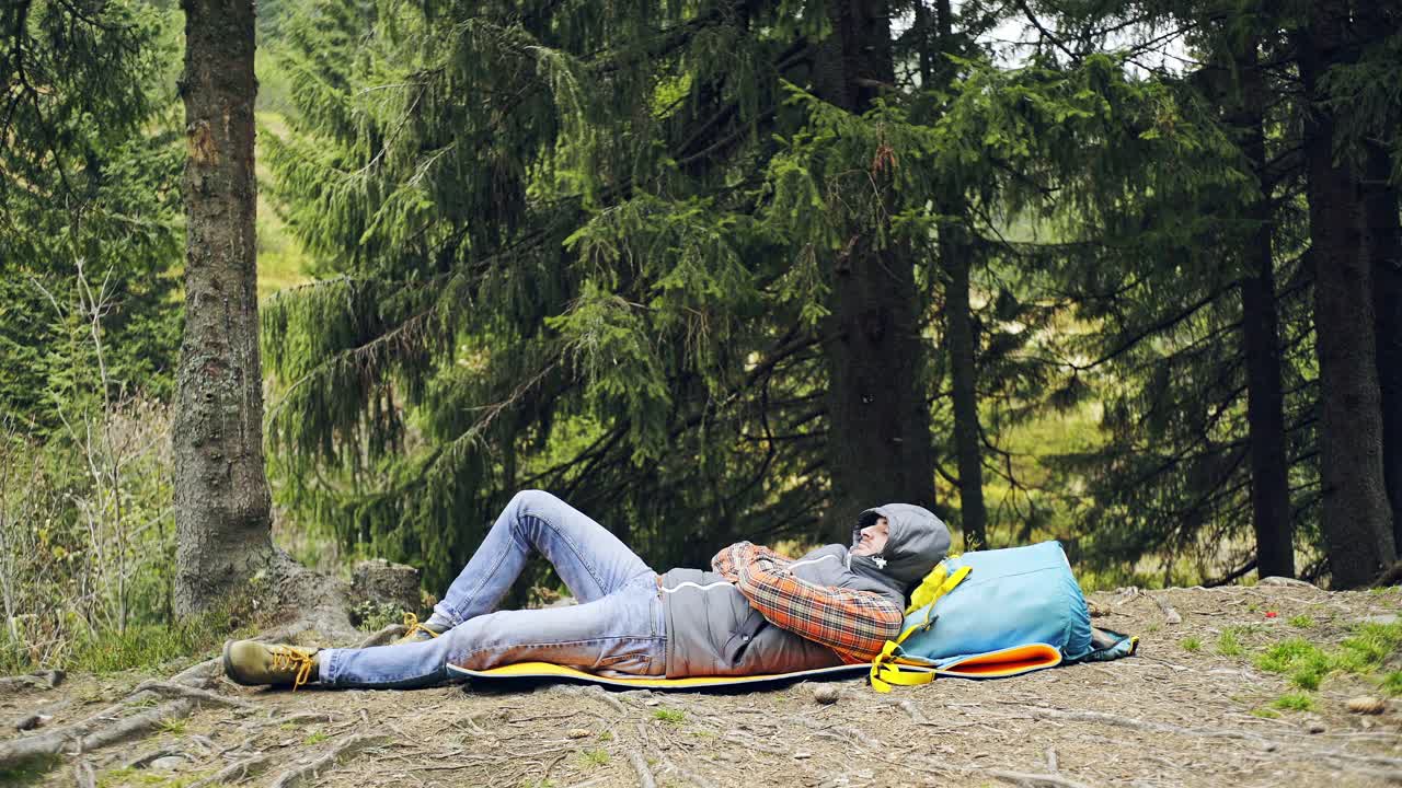 男人睡在树林的垫子上视频下载