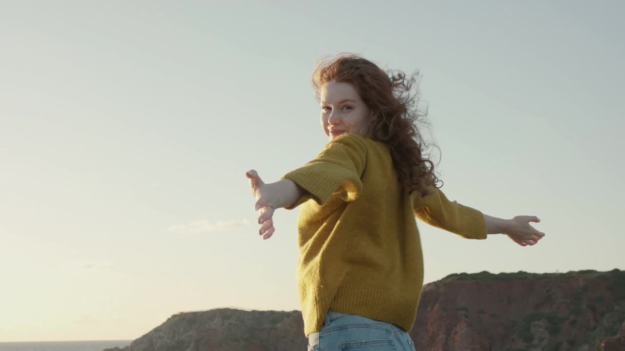 年轻女子在海边悬崖上享受海风视频素材