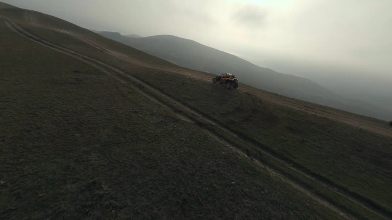 拍摄跟随运动fpv无人机极端橙色小车赛车速度骑在丘陵地形视频下载