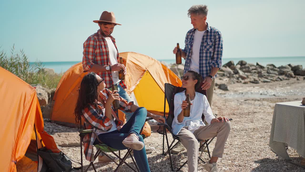 四个成年人朋友旅行者享受暑假和喝冰啤酒在炎热的晴天露营在海岸视频下载
