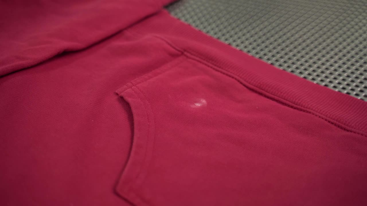 女工人站在工作场所的腹部，用专业的干洗工具清除女夹克上的灰尘。熟练的员工用化学去污剂和烘干机喷洒衣物视频下载