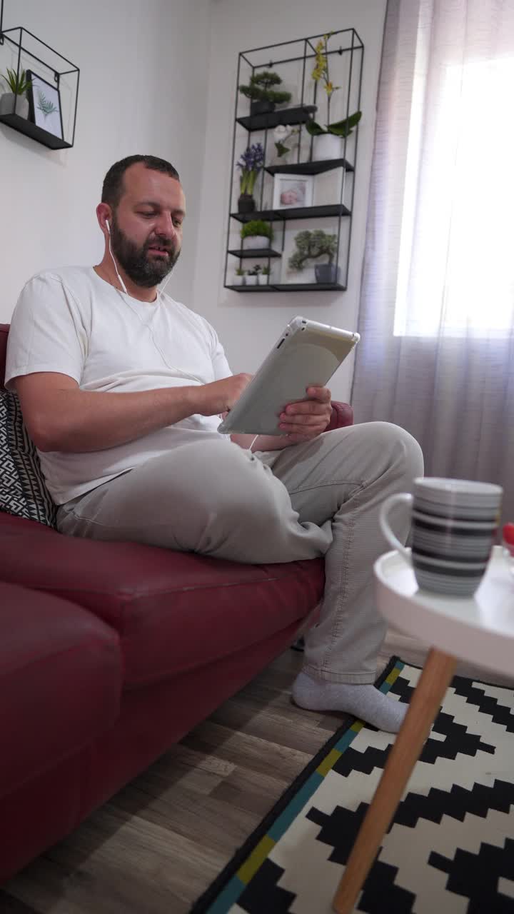 男人戴着耳机在家里用数码平板电脑视频素材