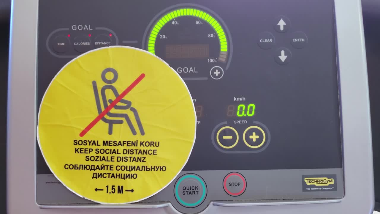在跑步机健身设备的闪烁数字显示屏上保持社交距离警告贴纸视频下载