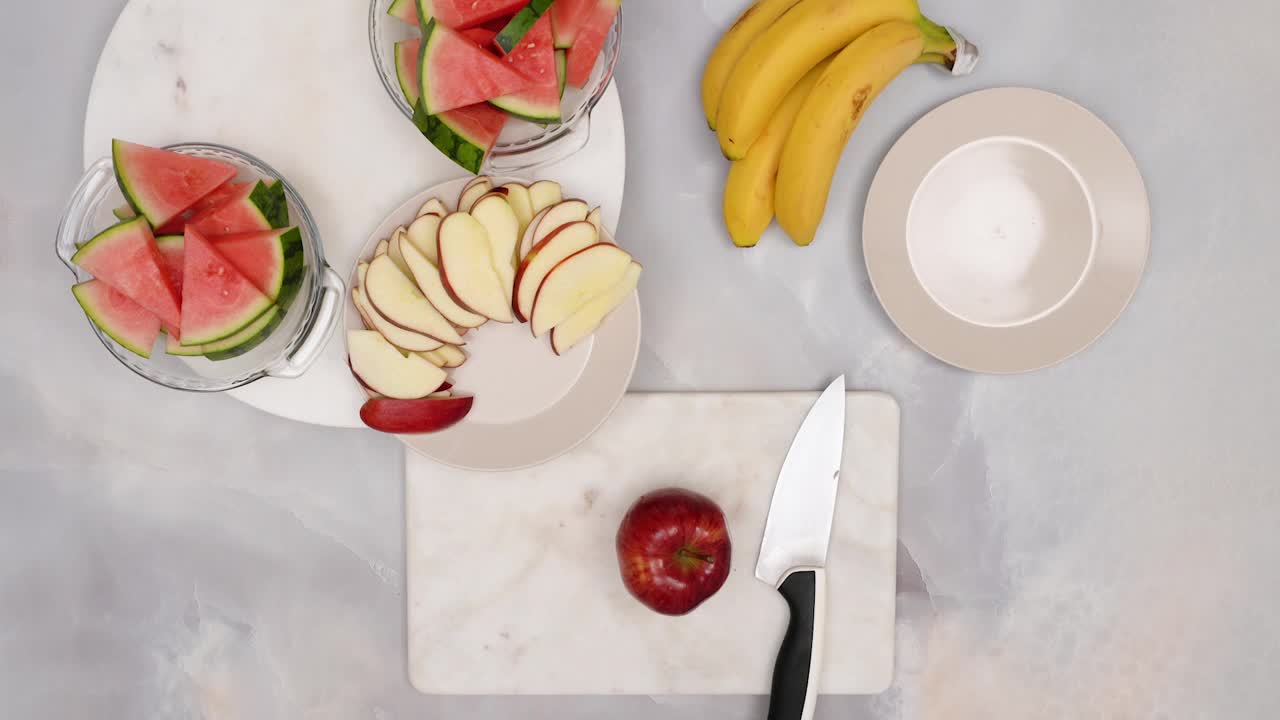 女子切红苹果，特写视频，平铺。水果沙拉，健康美味的甜点食谱视频下载