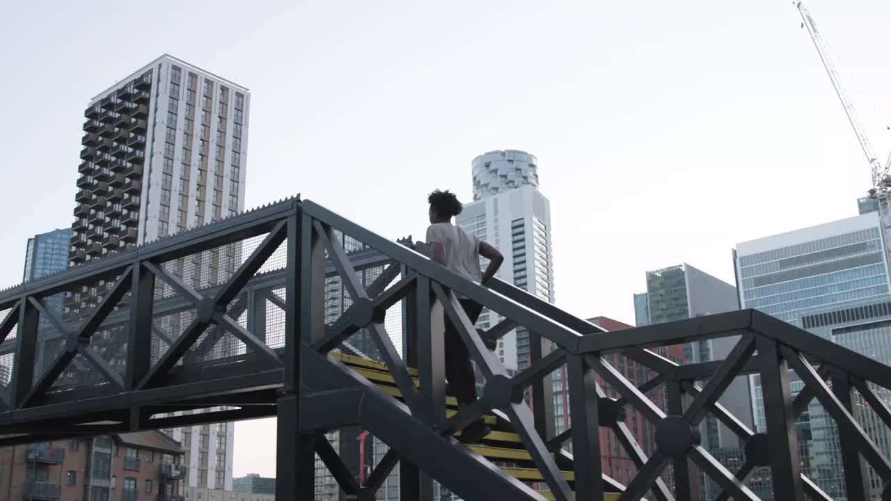 一位女性跑步者正跑过城市中的一座人行天桥视频下载