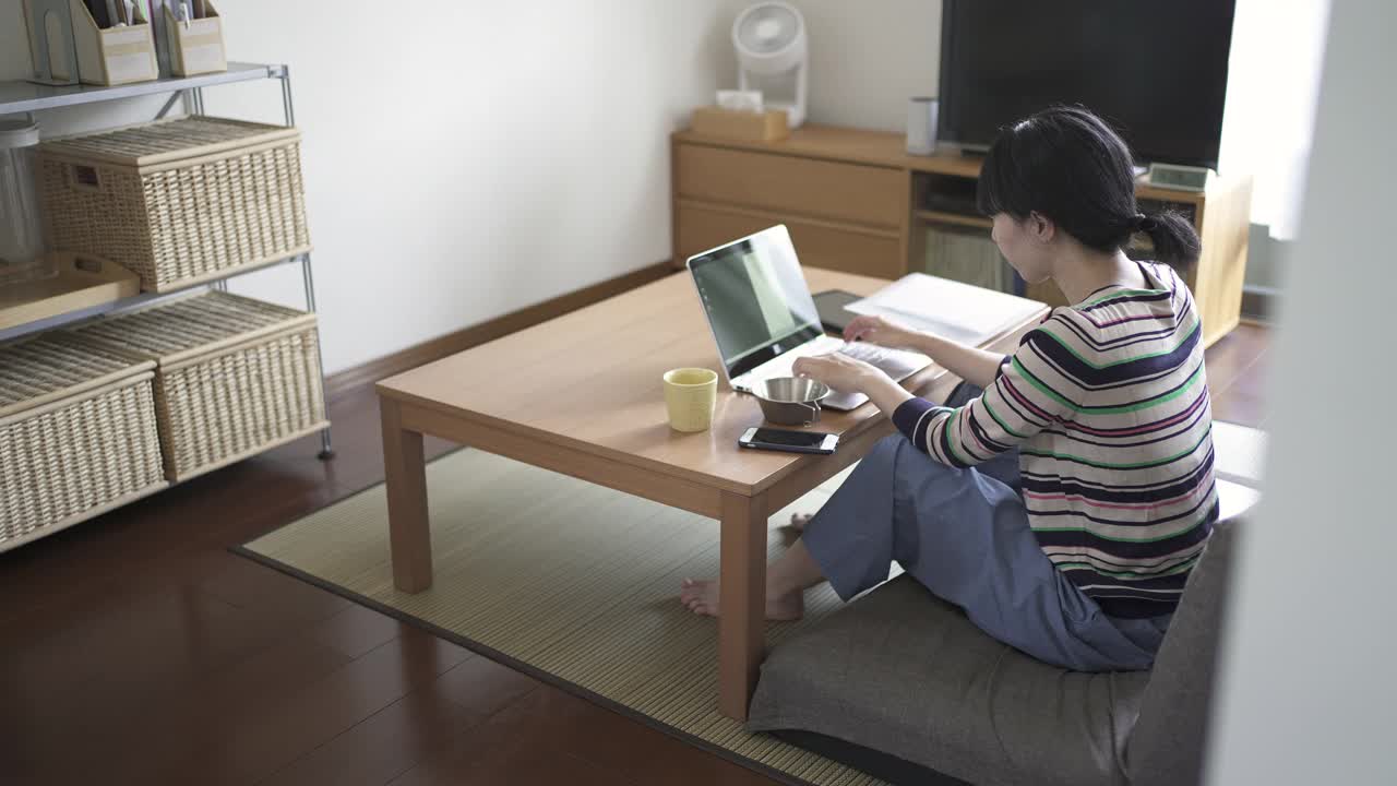 在家工作，在客厅使用电脑的中年妇女。视频下载