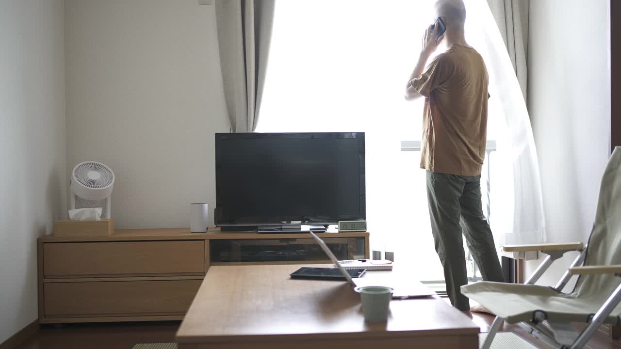 中年男性在家工作，在客厅使用智能手机。视频下载