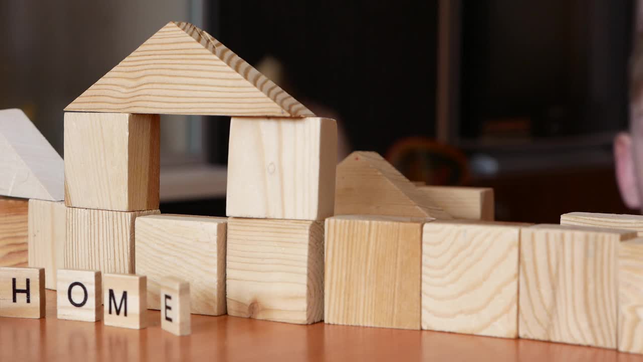 这个男孩用木制玩具零件盖了一所房子。一个高加索学龄前男孩在家里玩得很开心，用立方体搭建房子。家庭梦想有一个特别的家。有选择性的重点视频下载