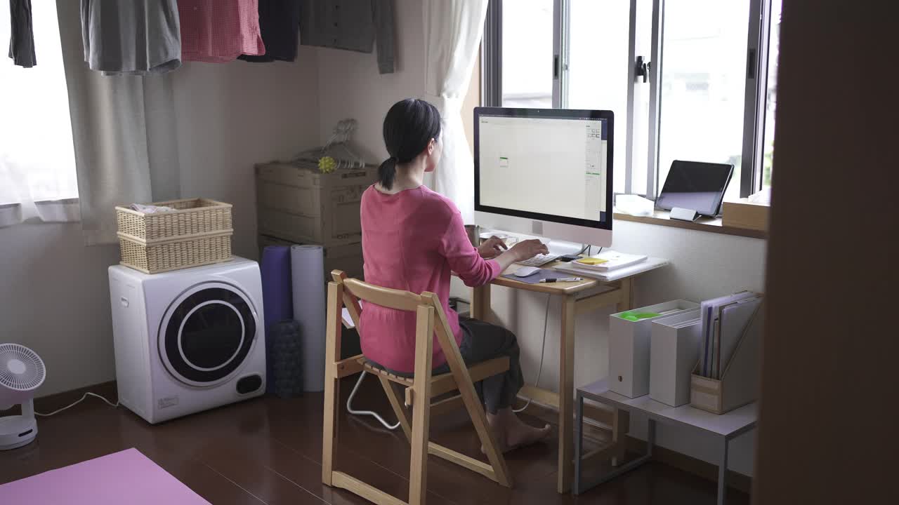在家工作，在房间里使用电脑的中年妇女。视频下载