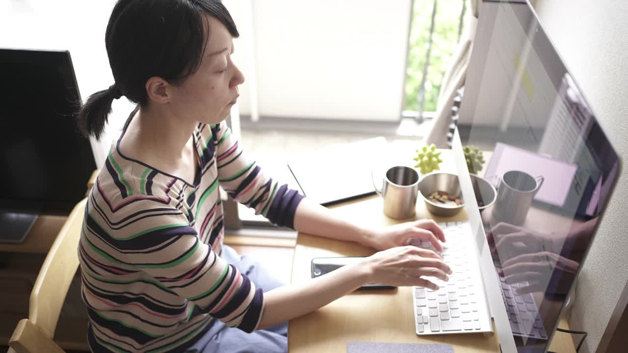 在家工作，在客厅使用电脑的中年妇女。视频下载