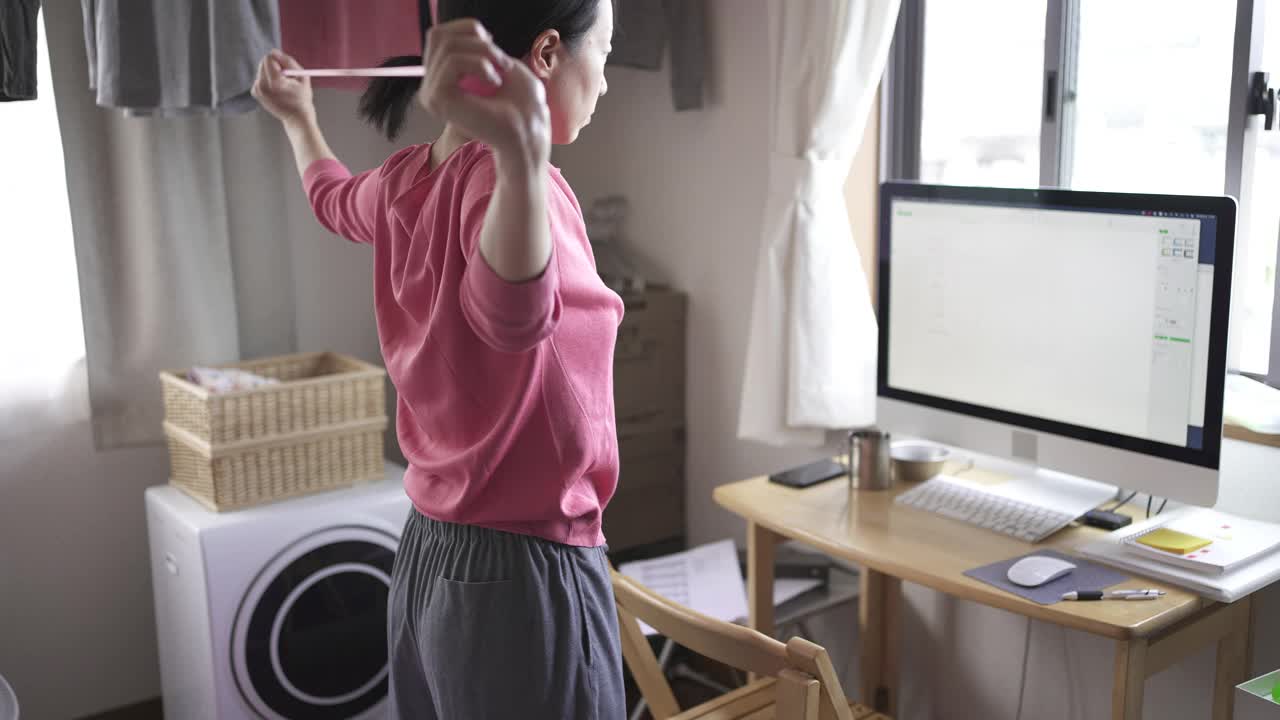 中年妇女在家工作时做一些简单的伸展运动。视频下载