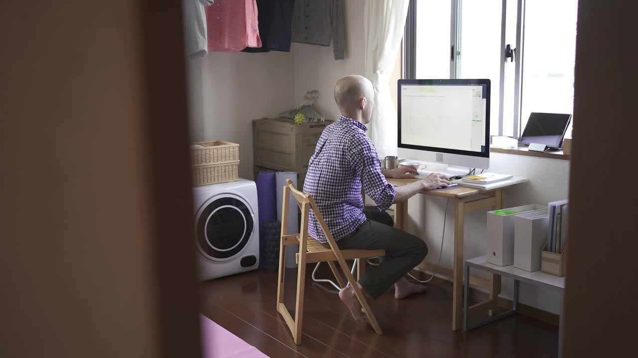 中年人在家工作，在房间里使用电脑。视频下载