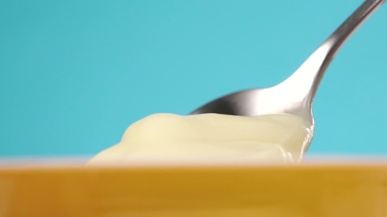 甜点勺从一个开着的黄色塑料容器中舀出甜美的奶油酸奶视频下载