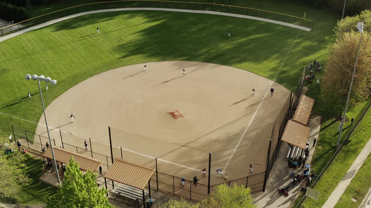 空中无人机拍摄。孩子们在阳光灿烂的日子里在公园打学校的棒球场视频下载
