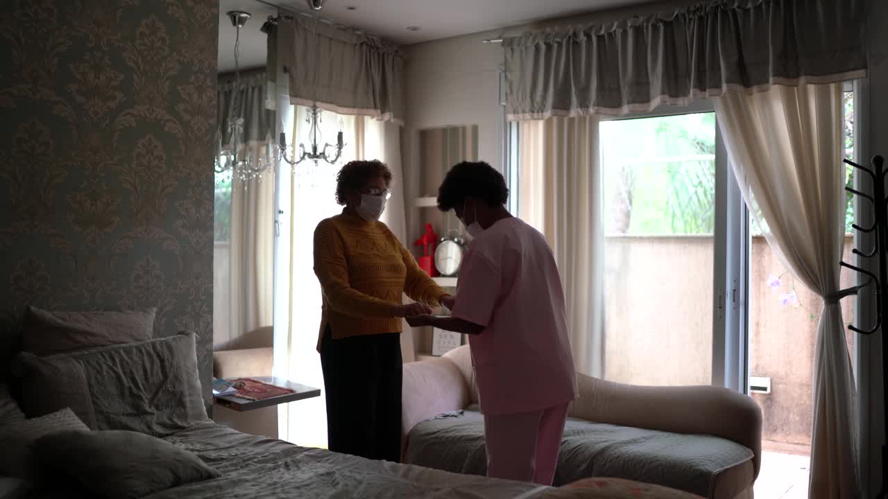 护士支持老年患者行走，佩戴防护口罩视频下载