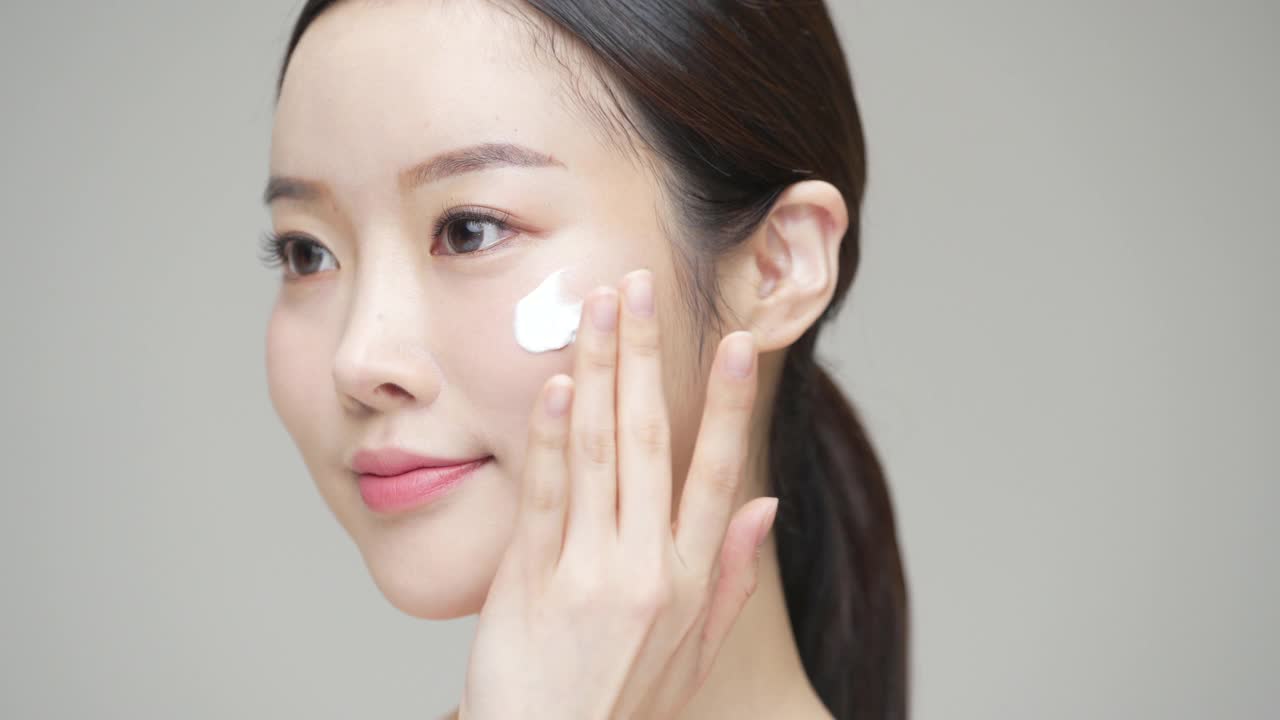 美丽-年轻女子在她的脸上涂面霜工作室/韩国视频下载