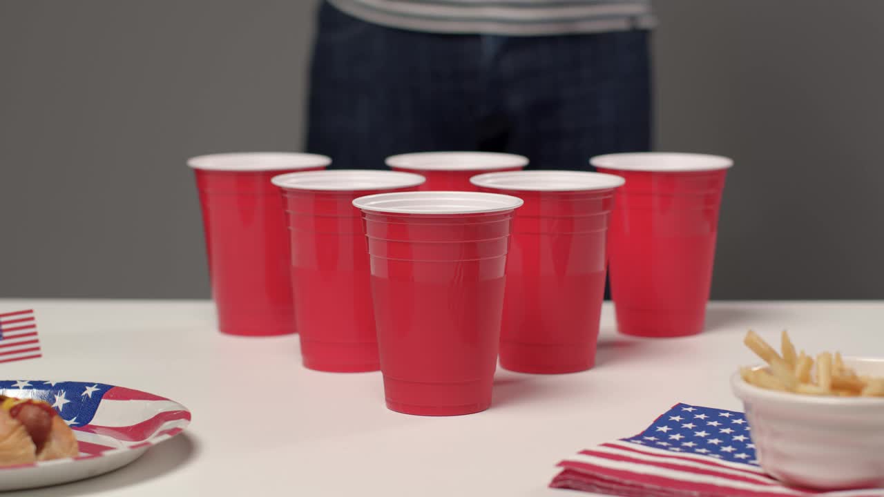 在啤酒乒乓游戏中，当一个人在背景中喝酒时，滑动射击接近杯子视频下载