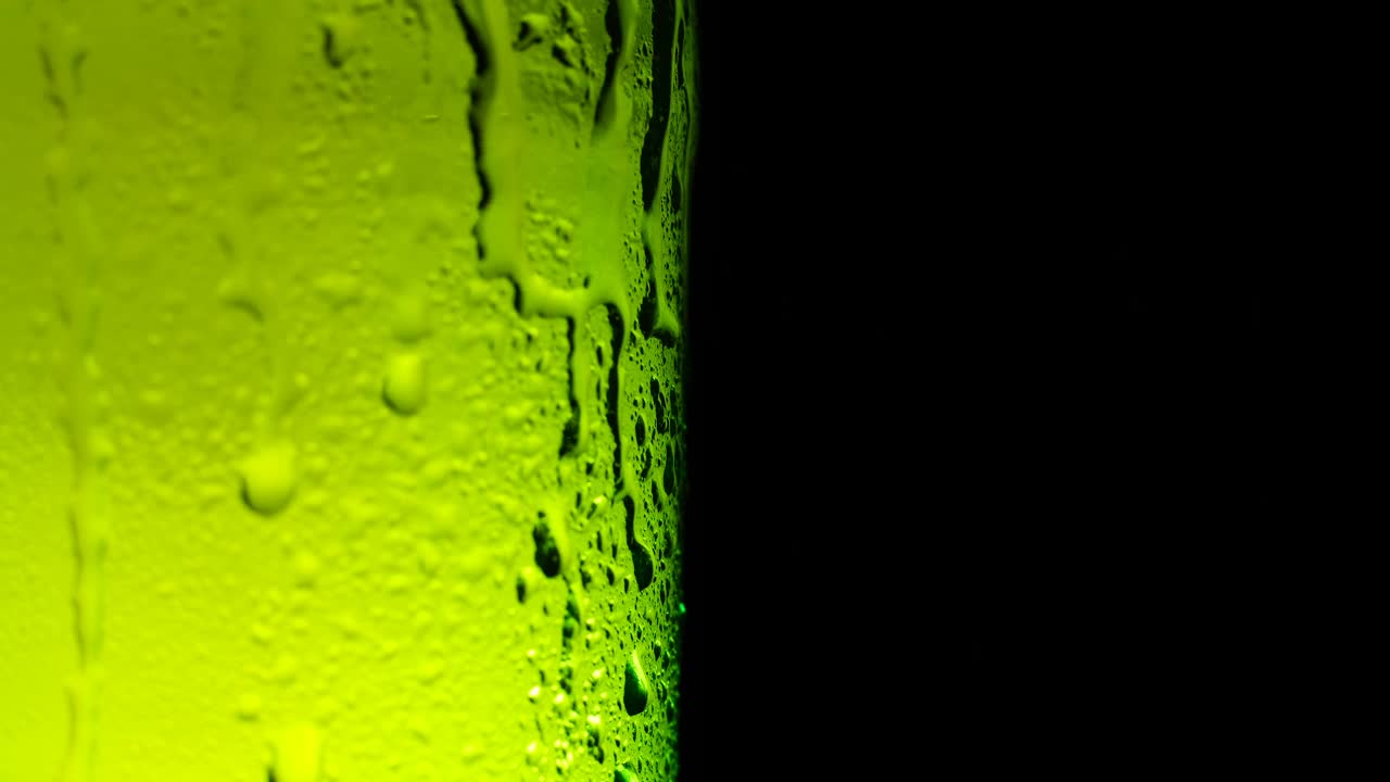 水滴落在啤酒杯上。水滴在绿色玻璃上近距离观看。视频素材