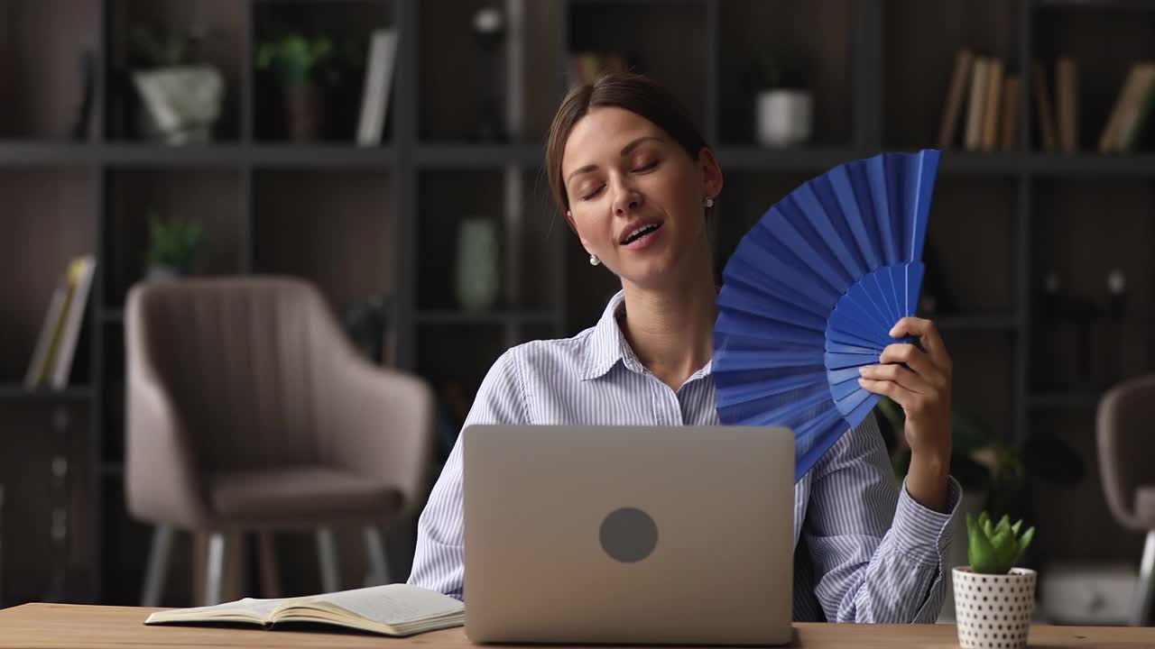 妇女用蓝色风扇为自己散热视频下载