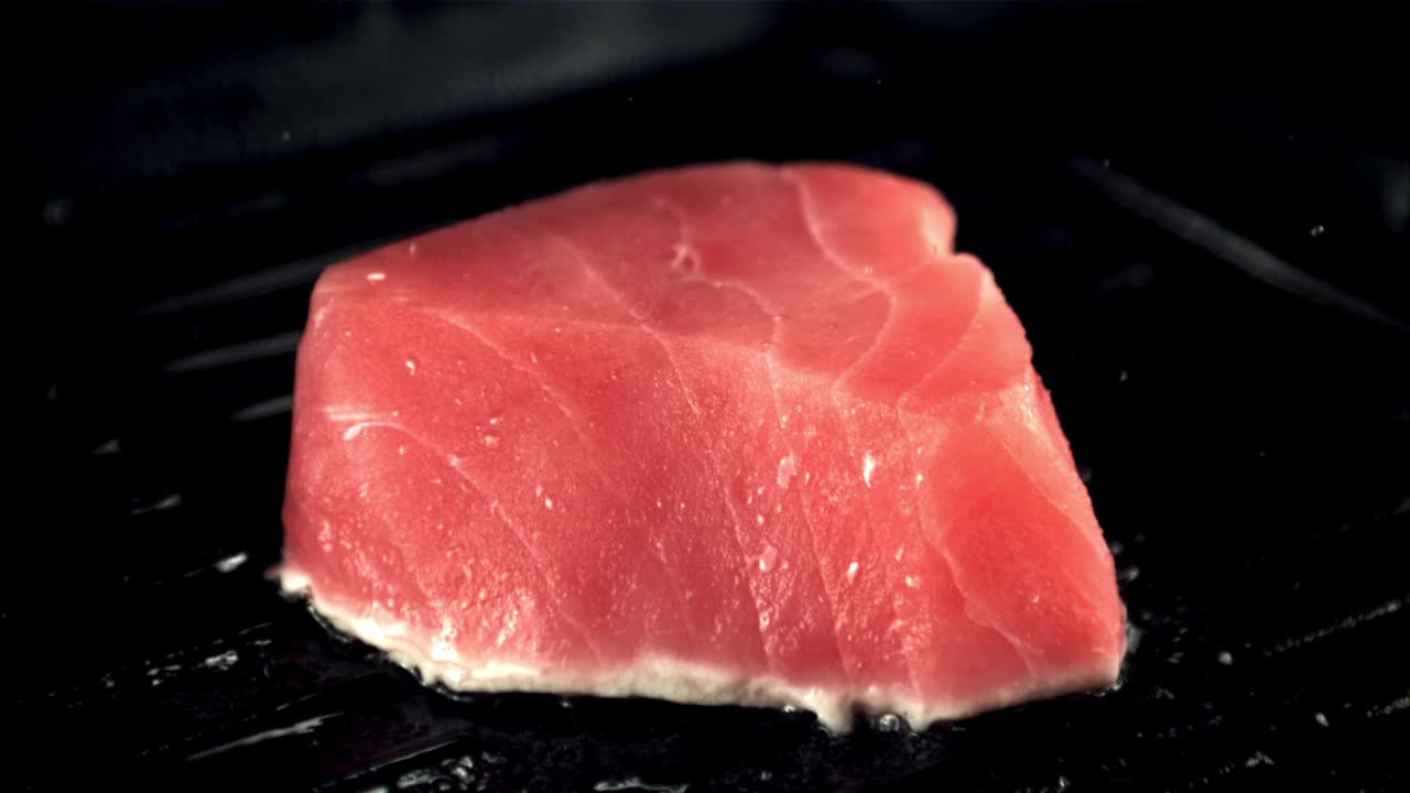 超级慢动作的金枪鱼牛排在烧烤锅里用油煎。用高速摄像机以每秒1000帧的速度拍摄。视频下载