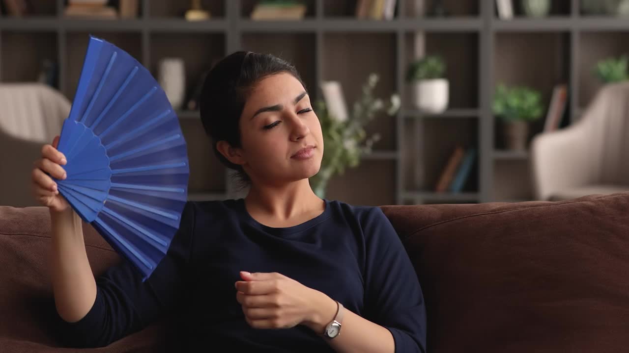 不健康的印度妇女用扇子给自己降温，减少室内的热量视频下载