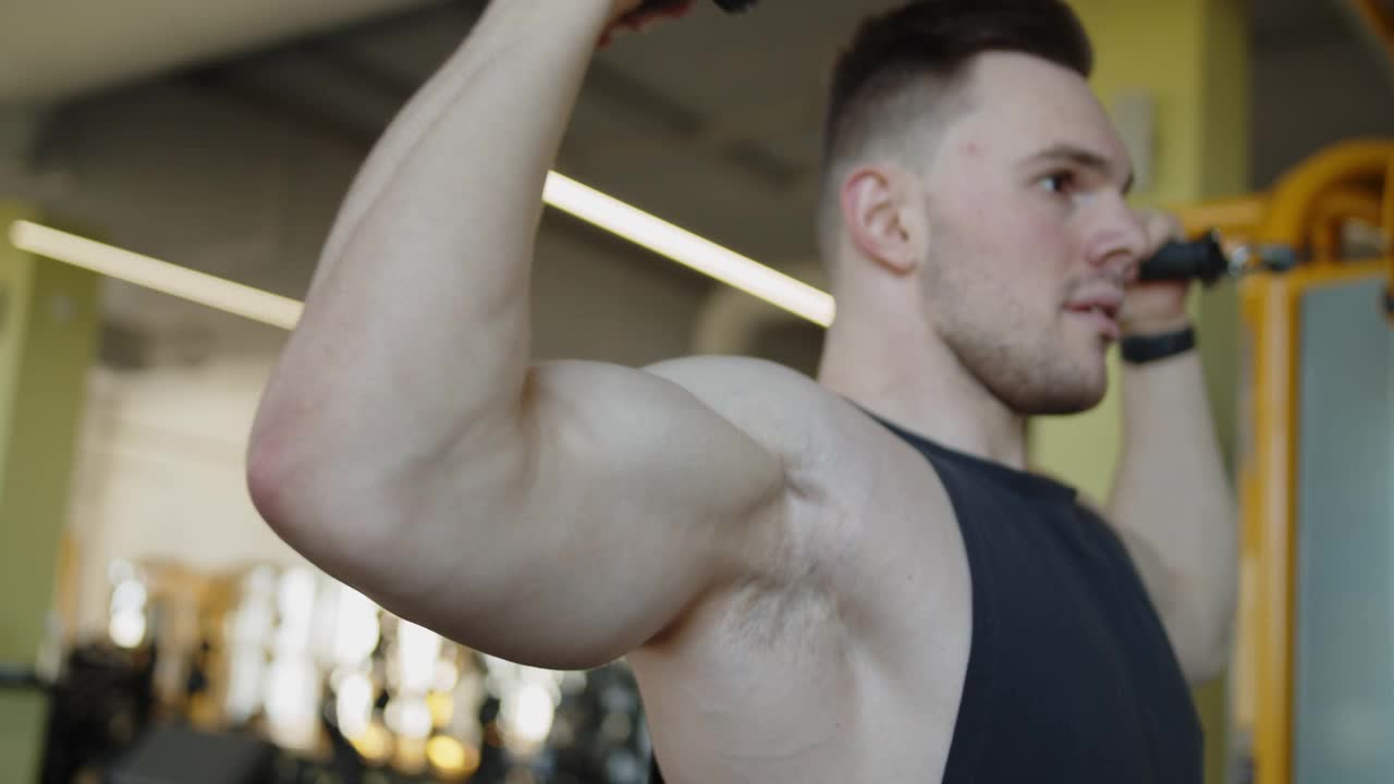年轻的肌肉运动员在一个现代的健身房做空中电缆卷视频下载