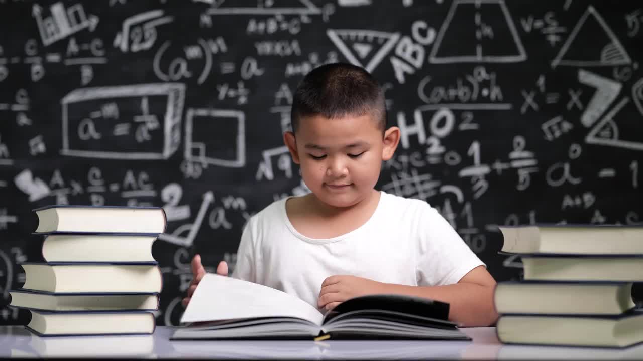 一个亚洲男孩坐在桌上看书视频下载