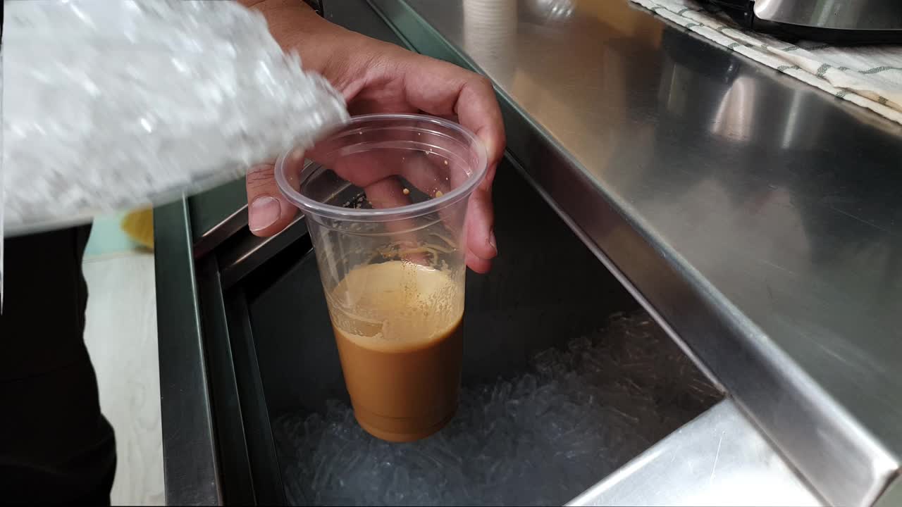 4K手将冰块从冰铲转移到塑料咖啡杯视频下载