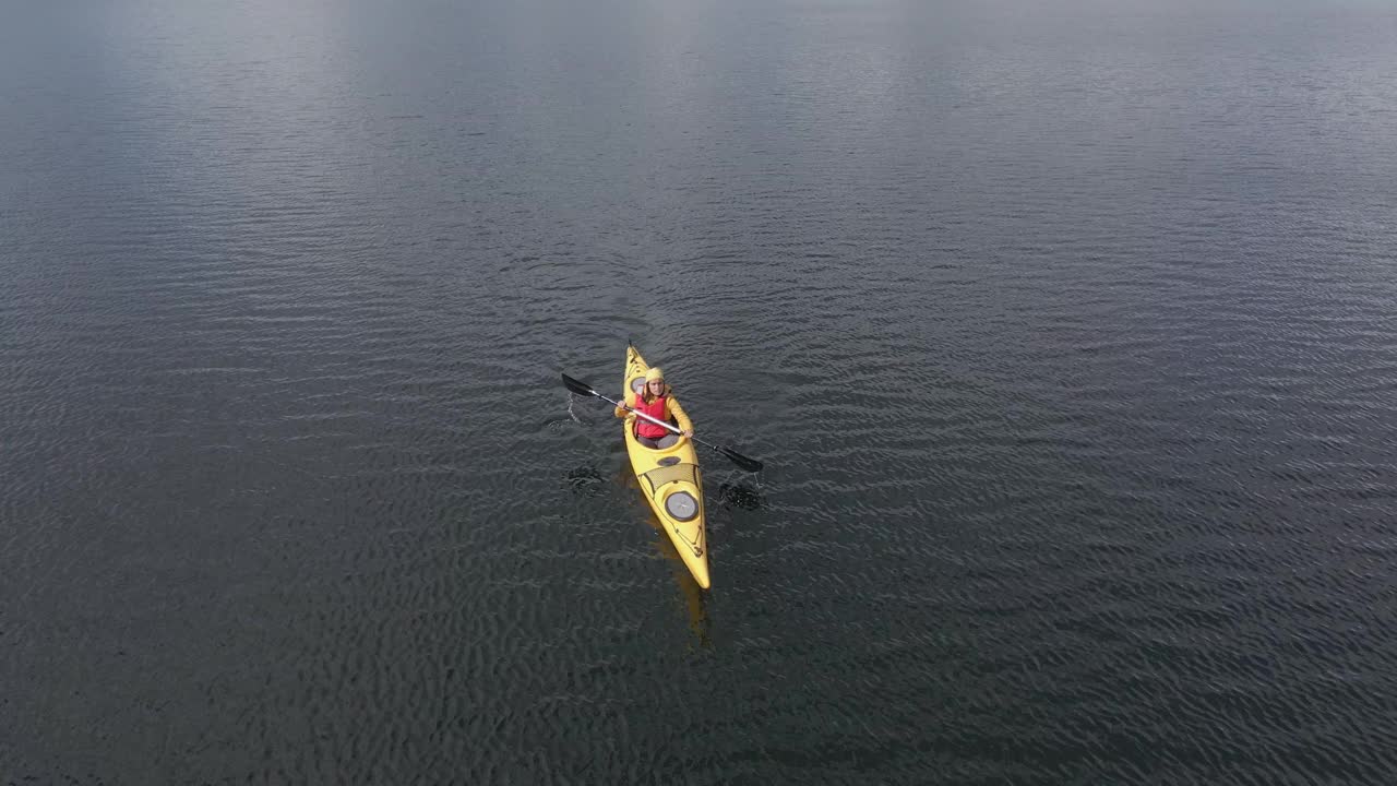 鸟瞰图的妇女皮划艇在山湖。划和生态旅游。缩小照片。视频下载